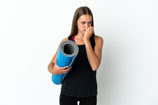 Mujer deportiva que va a clases de yoga mientras sostiene una estera sobre fondo blanco aislado que tiene dudas