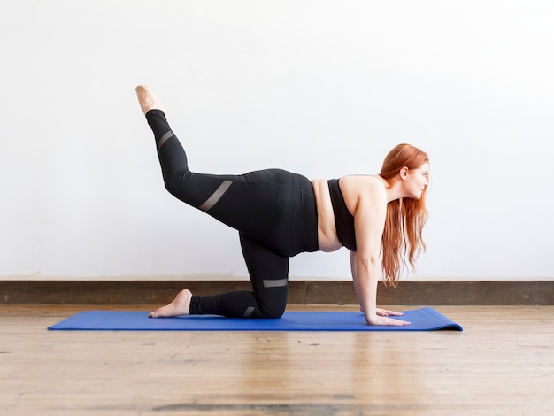 Mujer deportiva que se extiende sobre una estera de yoga