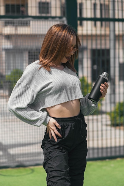 Mujer deportiva que sostiene una botella de agua negra