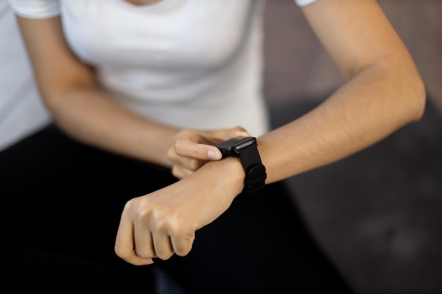 Mujer deportiva reiniciando el rastreador de fitness mientras está sentada en el suelo