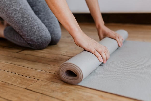 Mujer deportiva rodando una estera de yoga