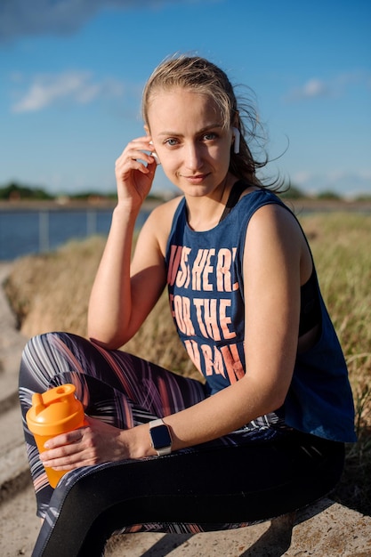 Mujer deportiva en ropa deportiva relajándose en el muelle en el fondo del agua