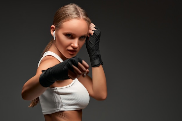 Mujer deportiva en vendas de boxeo en el estudio mirando a la cámara Fondo gris aislado Copiar espacio