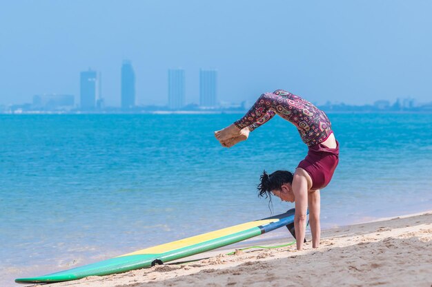 Foto mujer deportiva yogini posando mayura pinchasana practica ejercicio de yoga a bordo del mar en un día relajante yoga es meditación y concepto de deporte saludable