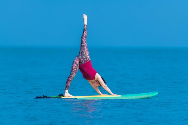 Foto mujer deportiva yogini posando mayura pinchasana practica ejercicio de yoga a bordo del mar en un día relajante yoga es meditación y concepto de deporte saludable