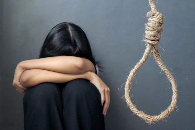 Mujer deprimida llora mientras sostiene una soga para suicidarse