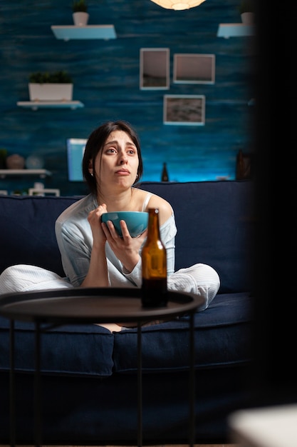 Mujer deprimida viendo una película de drama en la televisión llorando con expresión emocional