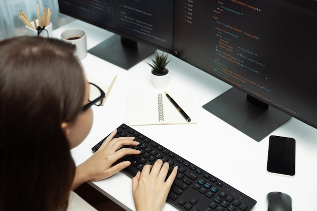 Foto la mujer desarrolladora codifica en la pantalla del portátil en la vista lateral trasera postula