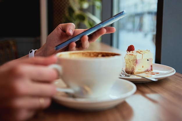 La mujer desayuna en el café usa el teléfono inteligente en el café