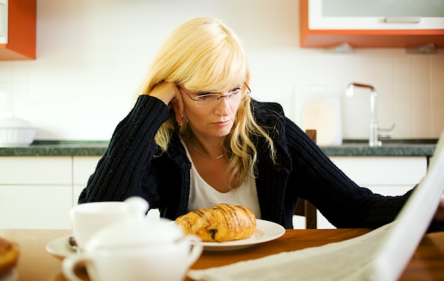 mujer desayunando y leyendo el periódico