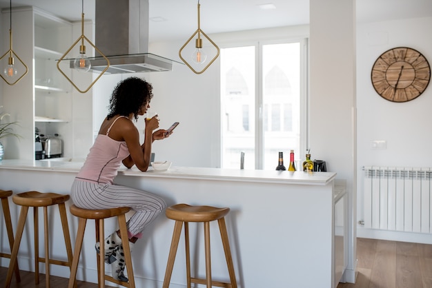 Mujer desayunando con teléfono móvil