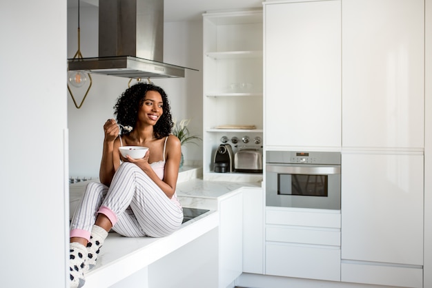 Mujer desayunando con teléfono móvil