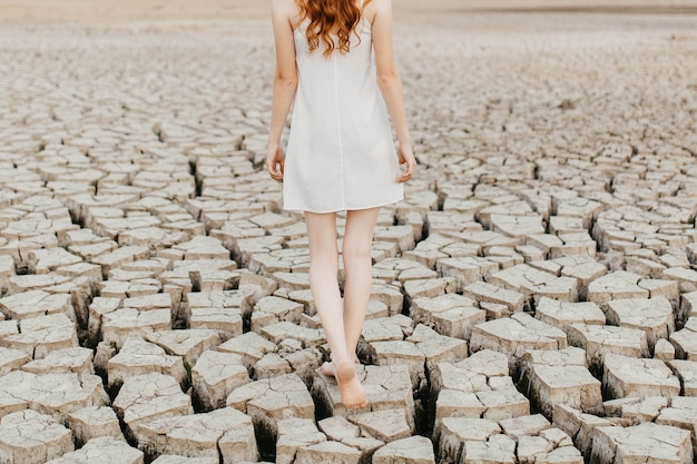 Mujer descalza caminando sobre el suelo seco del lago.