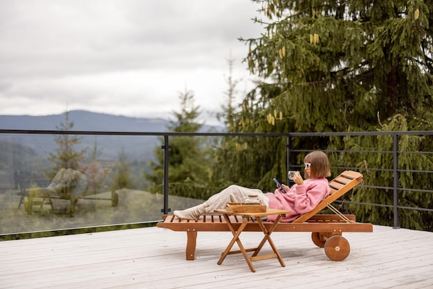 La mujer descansa en la terraza en las montañas