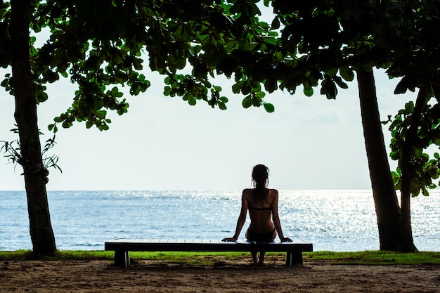 Mujer descansando en un banco de playa. Concepto de vacaciones de verano