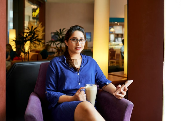 Mujer descansando con café en la cafetería