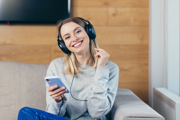 Mujer descansando en casa escuchando música divertida con auriculares