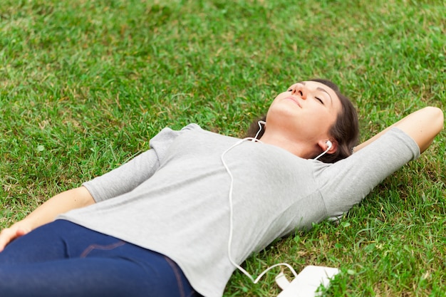 Mujer descansando en la hierba mientras escucha música