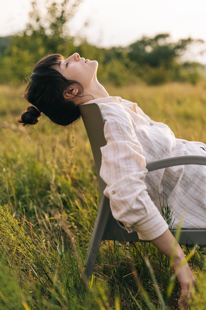 Una mujer descansando en una silla en un campo de hierba.