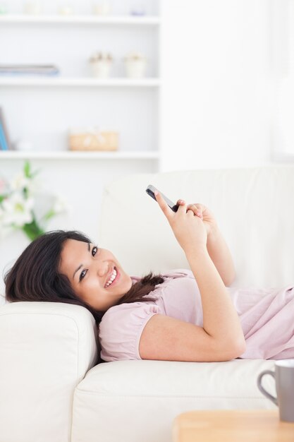 Mujer descansando en un sofá mientras sostiene un teléfono