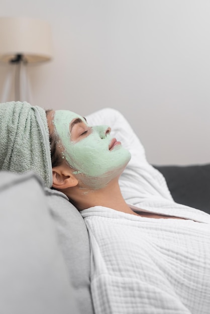 Foto mujer descansando en el sofá saboreando una máscara hidratante facial para una experiencia de spa tranquila en casa