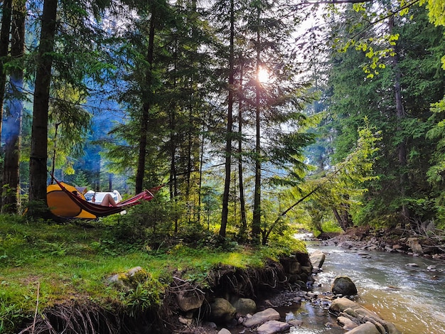 Mujer descansando tendido en una hamaca en el camping vacaciones de verano bosque verde