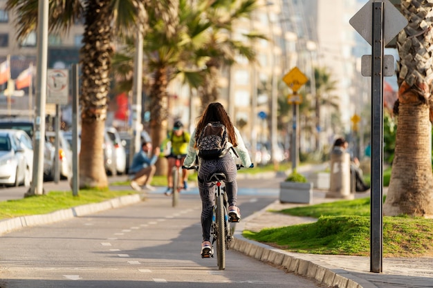 Mujer desconocida andar en bicicleta en ciclovía al atardecer en La Serena