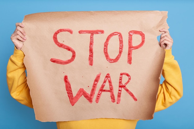 Mujer desconocida durante una manifestación pacífica contra la guerra sosteniendo un cartel de papel con la inscripción Stop War activista con un cartel contra la guerra que defiende la paz mundial Gloria a Ucrania