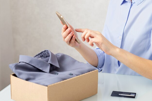 Foto una mujer desembala una caja de cartón con ropa, compra productos en línea, concepto de entrega.