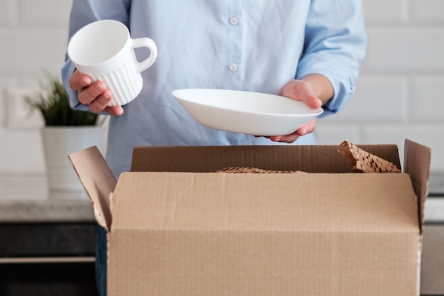 Una mujer desempaca una caja con platos nuevos.