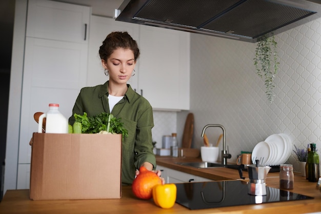 Mujer desempacando la entrega de comestibles frescos en la cocina