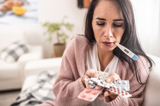 Mujer desesperada con gripe sostiene varios paquetes de medicamentos sin saber cuál elegir.