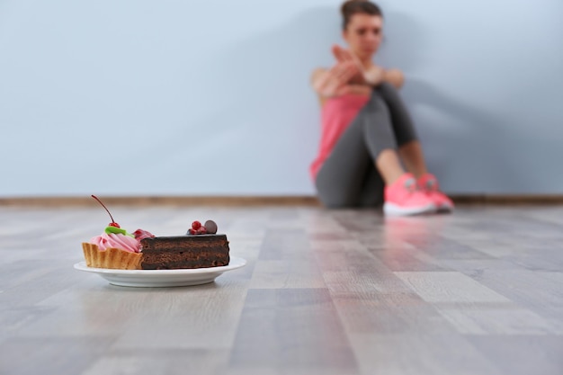 Foto mujer desesperada sentada en el suelo sobre fondo de pared gris concepto de trastorno alimentario