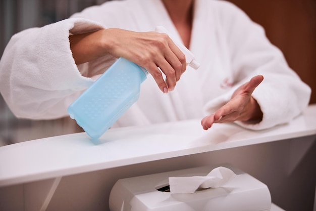 Mujer desinfectando sus manos en el mostrador de recepción del salón de belleza