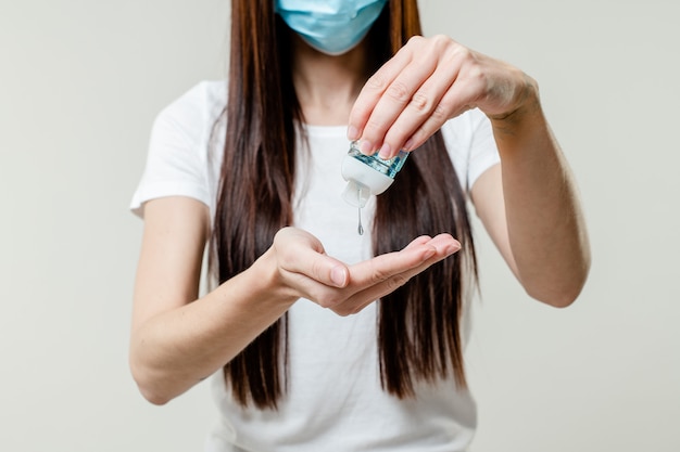 Foto mujer con desinfectante para manos con máscara