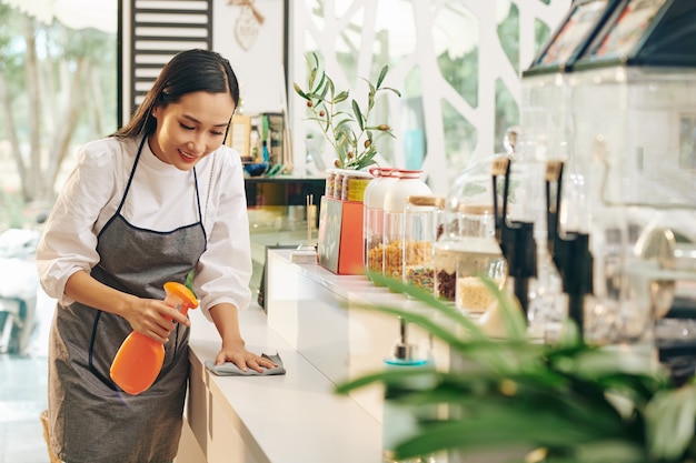 Mujer desinfectar superficies en cafe