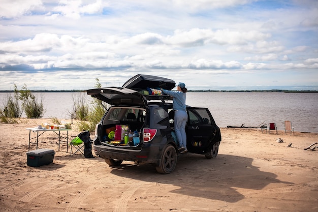 Mujer despegando equipo turístico de caja de techo en el río.