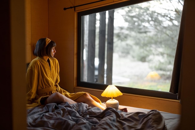 La mujer se despierta en la pequeña habitación de la cabaña de madera en la naturaleza