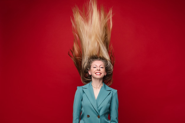 Mujer despreocupada feliz en chaqueta azul con el pelo en movimiento.