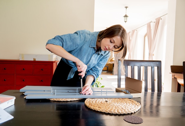 Foto mujer con destornillador instalando un mueble en casa personalmente