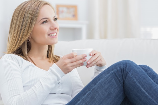 Mujer con el día de la taza de café soñando en el sofá