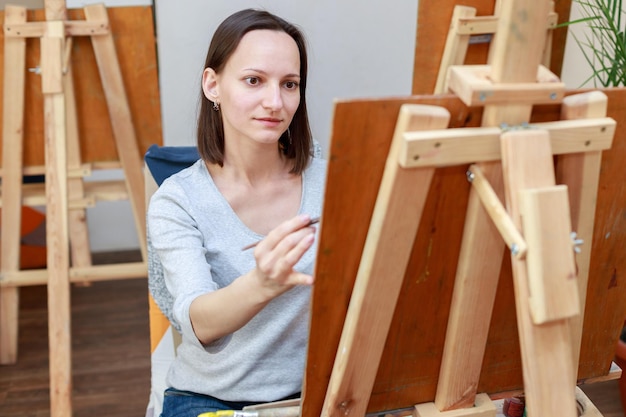 Una mujer dibuja en un caballete en un pasatiempo de clase de arte