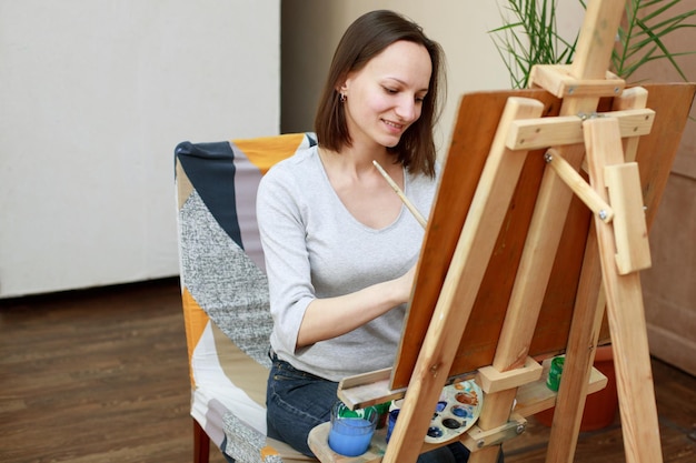 Una mujer dibuja detrás de un caballete en una clase de arte.