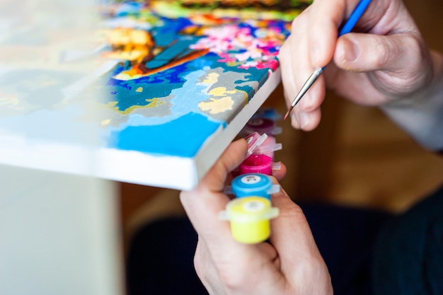 Mujer dibuja con un pincel pintando por números sobre lienzo Cuadro por números Dibujo sobre lienzo