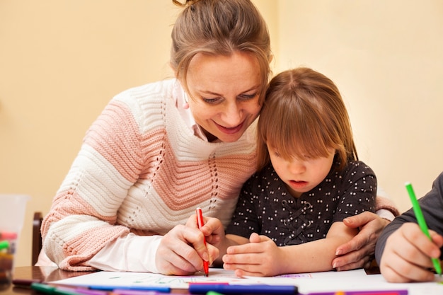 Foto mujer dibujando con niña con síndrome de down