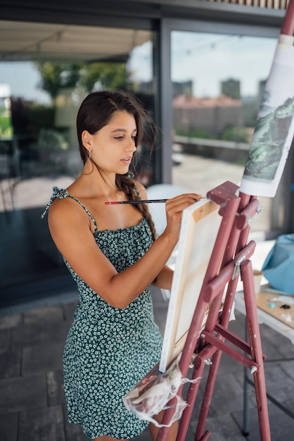 Mujer dibujando su imagen sobre lienzo con colores al óleo