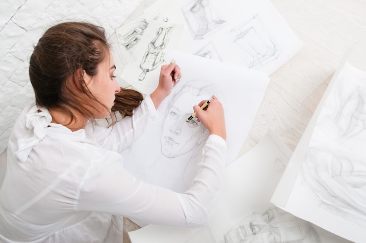 Foto mujer dibujo retrato a lápiz en el piso en el taller