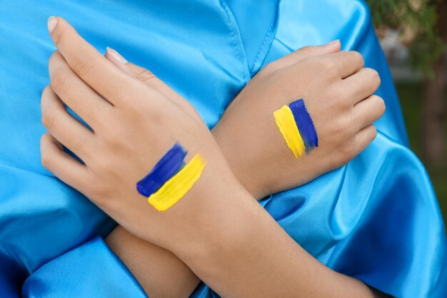 Foto mujer con dibujos de bandera ucraniana en manos al aire libre closeup