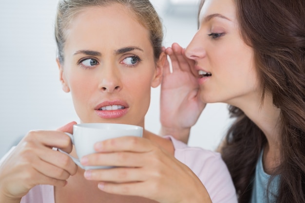 Mujer diciendo secreto a su amigo