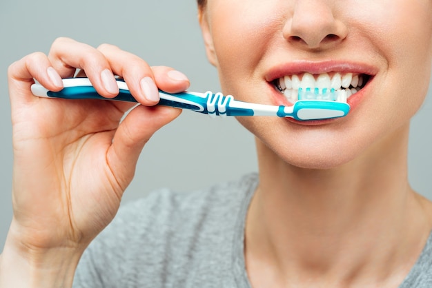 Mujer con dientes blancos sanos sostiene un cepillo de dientes y sonríe concepto de higiene bucal